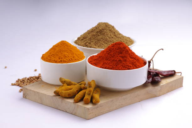 Indian spices_Chilli, Turmeric and Coriander  are the basic three spices  used for indian curry or dishes, arranged  in awhite bowls and placed on a wooden base with white texture